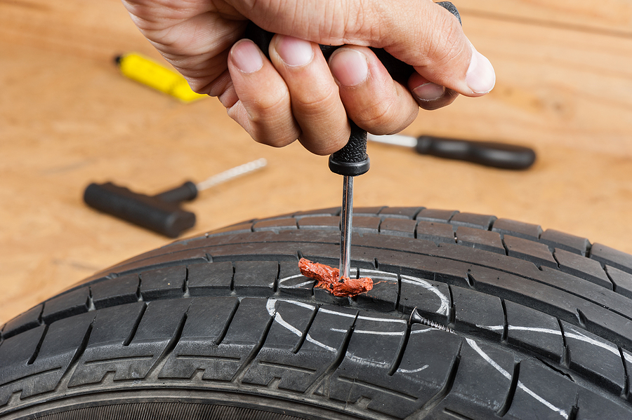Close-up of a technician inserting a tire plug to fix a punctured tire during a mobile service call.